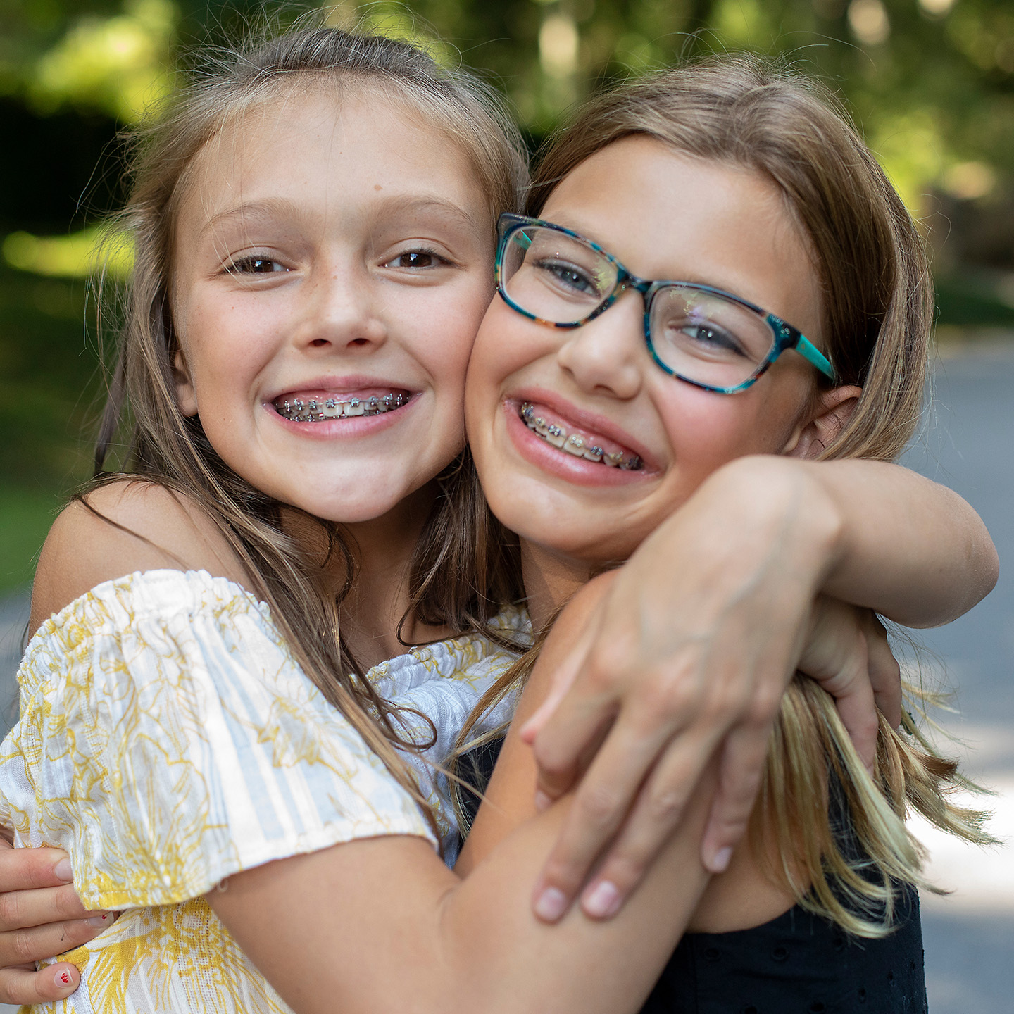 Two young girls hugging each other with smiles on their faces.