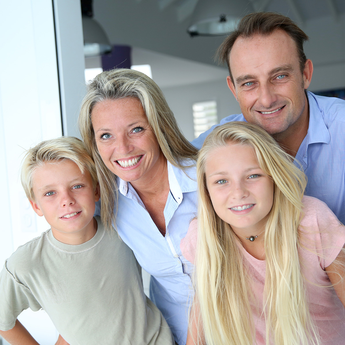 The image shows a family of four - a man, woman, and two children - posing for a photograph together with smiles on their faces.